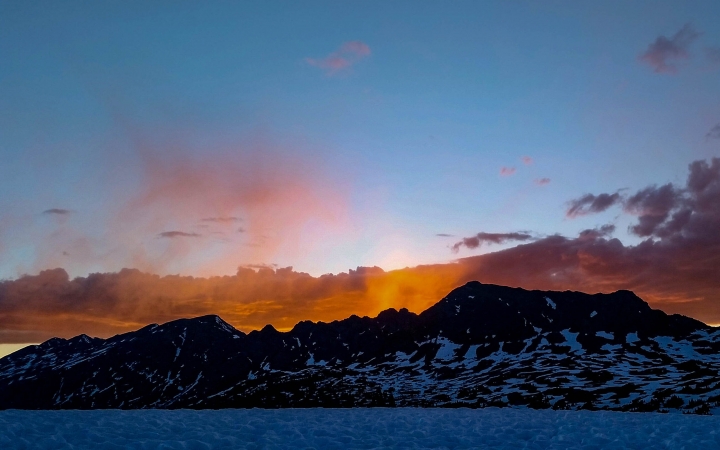 the sun rises behind a mountainous ridge